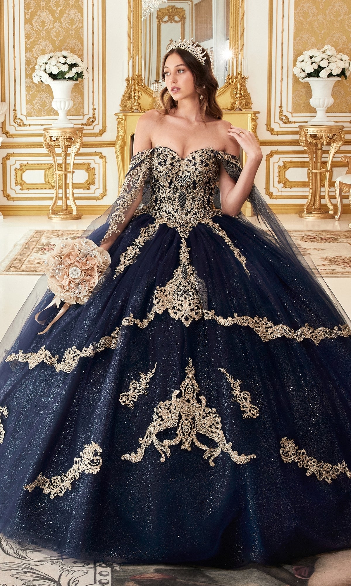 A woman in the Ladivine 15711 Quinceañera Dress with gold embroidery stands in an ornate, gold-accented room, holding a bouquet and wearing a tiara.